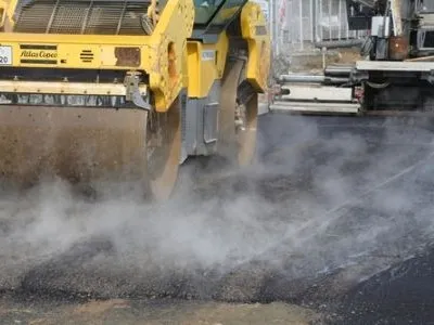 crews in a steamroller applying asphalt