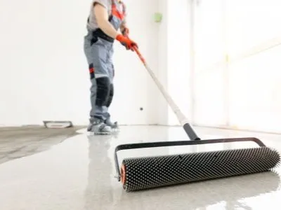 person raking self-leveling concrete material